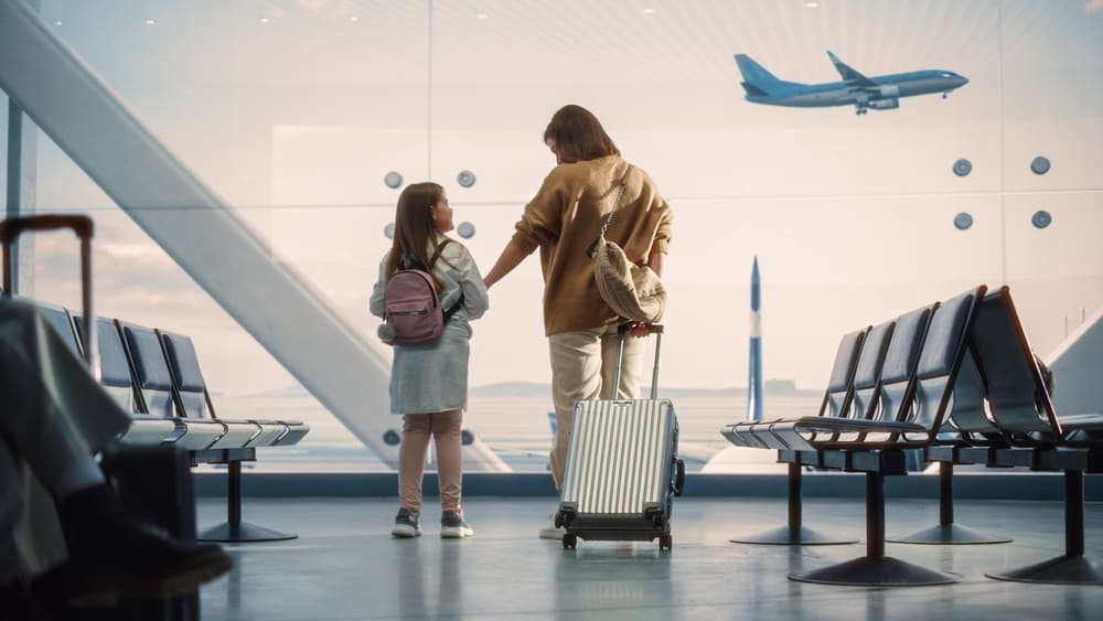 Beautiful Mother and Cute Little Daughter Wait for their Vacation Flight, Looking out of Window for Arriving and Departing Airplanes.