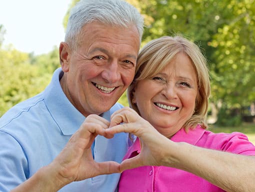 Portrait of Elderly Couple Smiling and Forming a Heart with Their Fingers