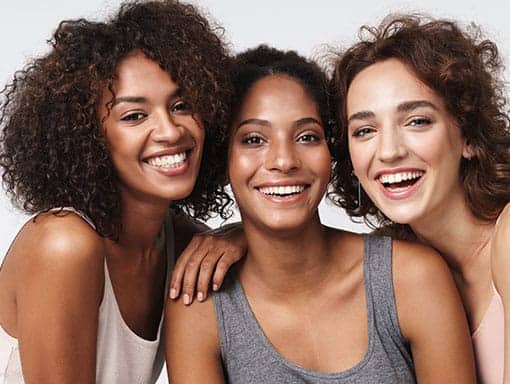 Portrait of Three Young Smiling Girls Looking at the Camera Reflecting Beautiful Skin