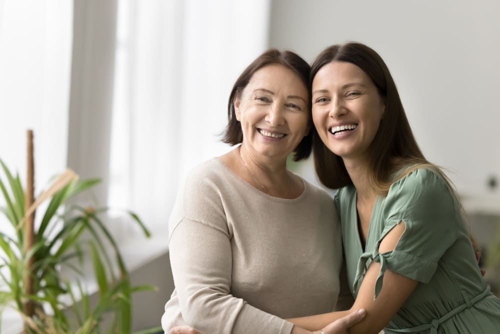 Cheerful elder mature mother and beautiful adult daughter woman hugging with heads touch